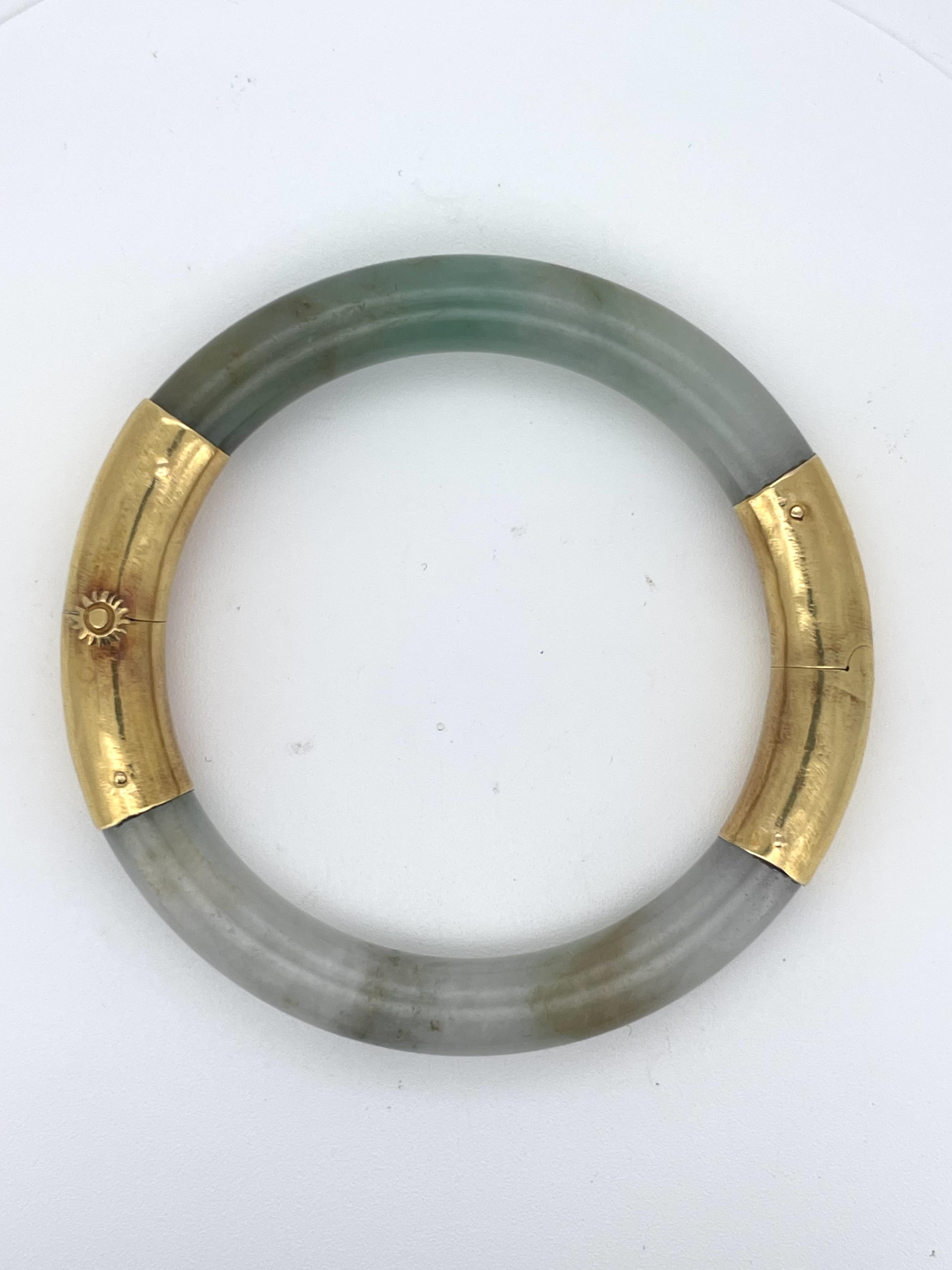 A jadeite and gold bangle, of hinged design, composed of a jadeite hoop mounted in gold, inner circumference approximately 15cm, stamped 22K